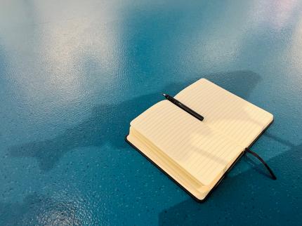 Ein Schreibbuch mit Stift auf dem Boden des Donauschw&auml;bischen Zentralmuseums mit dem Schatten eines Fisches