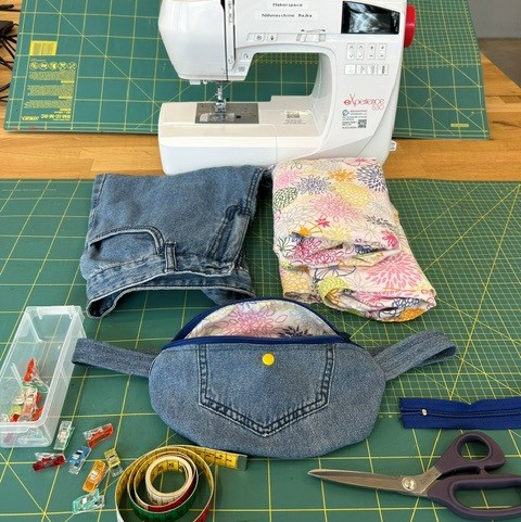 Eine Nähmaschine, daneben Stoffe und Nähutensilien