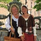 Zwei lächelnde Gästeführerinnen in (märchenhaftem) historischen Gewand mit weissen Hauben
