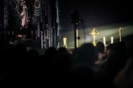 Scheinwerfer fällt im dunkeln auf die beleuchtete Monstranz