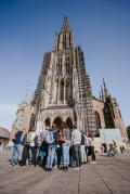 Gäste mit Gästeführerin auf dem Münsterplatz mit Ulmer Münster im Hintergrund