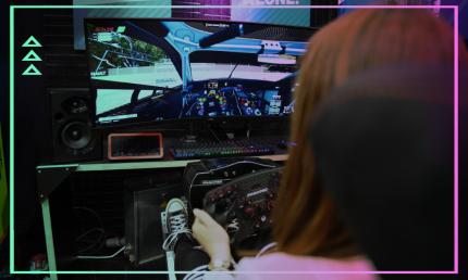 Eine junge Frau sitzt im Sim Racing Rig und spielt ein Autorennen im Rennsimulator.