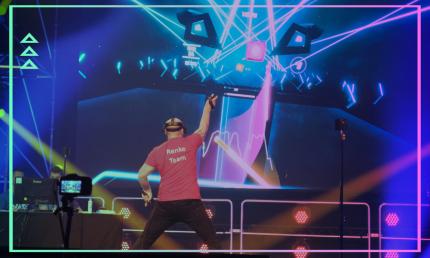 Jemand spielt das Spiel Beat Saber durch eine VR Brille. Auf dem Bildschirm kann man sehen, wie er Blöcke zerschlägt.