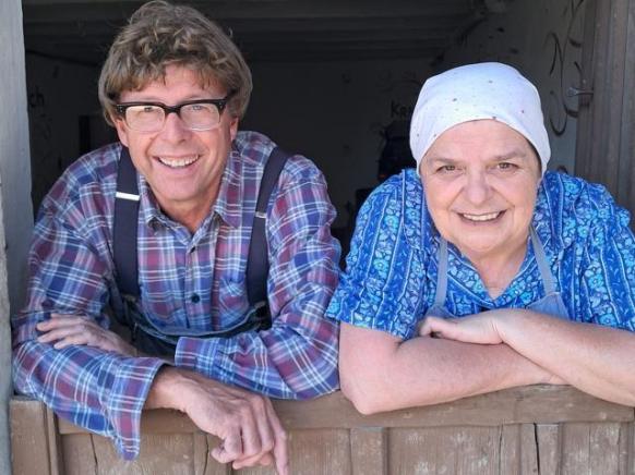 Hillu und Mattheis lehnen an einer Gittert&uuml;r. Lachen in die Kamera.