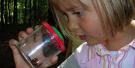 Kind, blondes Mädchen, schaut in ein Glas