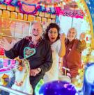 Sybille Bullatschek auf einem Karussell mit zwei Senior*innen