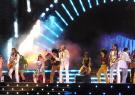 Abbildung einer Musikalische Szene der Show "Massachusetts - Bee Gees Musical" mit der Band im Vordergrund der Bühne, stehend an Mikrofonen und Tänzern im Hintergrund