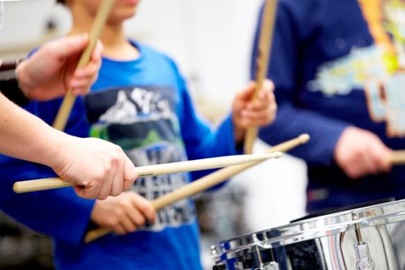 Kinder spielen mit Schlägeln auf Trommeln