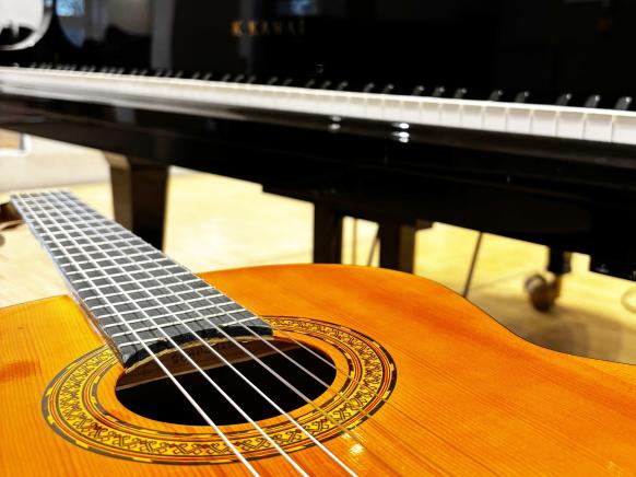 Eine Gitarre im Vordergrund eines Klaviers