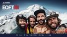 Vier Männer mit Glitzer im Gesicht vor einer schneebedeckten Berglandschaft