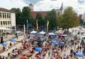 Blick auf den Neu-Ulmer Rathausplatz mit Biergarnituren, Besuchern sowie Gastronomie- und Infoständen