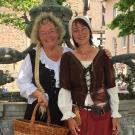 Zwei l&auml;chelnde G&auml;stef&uuml;hrerinnen in (m&auml;rchenhaftem) historischen Gewand mit weissen Hauben