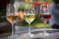 Drei Weingläser, gefüllt mit Weiß-, Rosé- und Rotwein