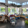 Die Stadtteilbibliothek Eselsberg von innen fotografiert. Im Vordergrund sieht man Büchertröge und Sitzgelegenheiten, im Hintergrund sieht man das Fenster nach außen