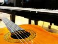 Eine Gitarre im Vordergrund eines Klaviers